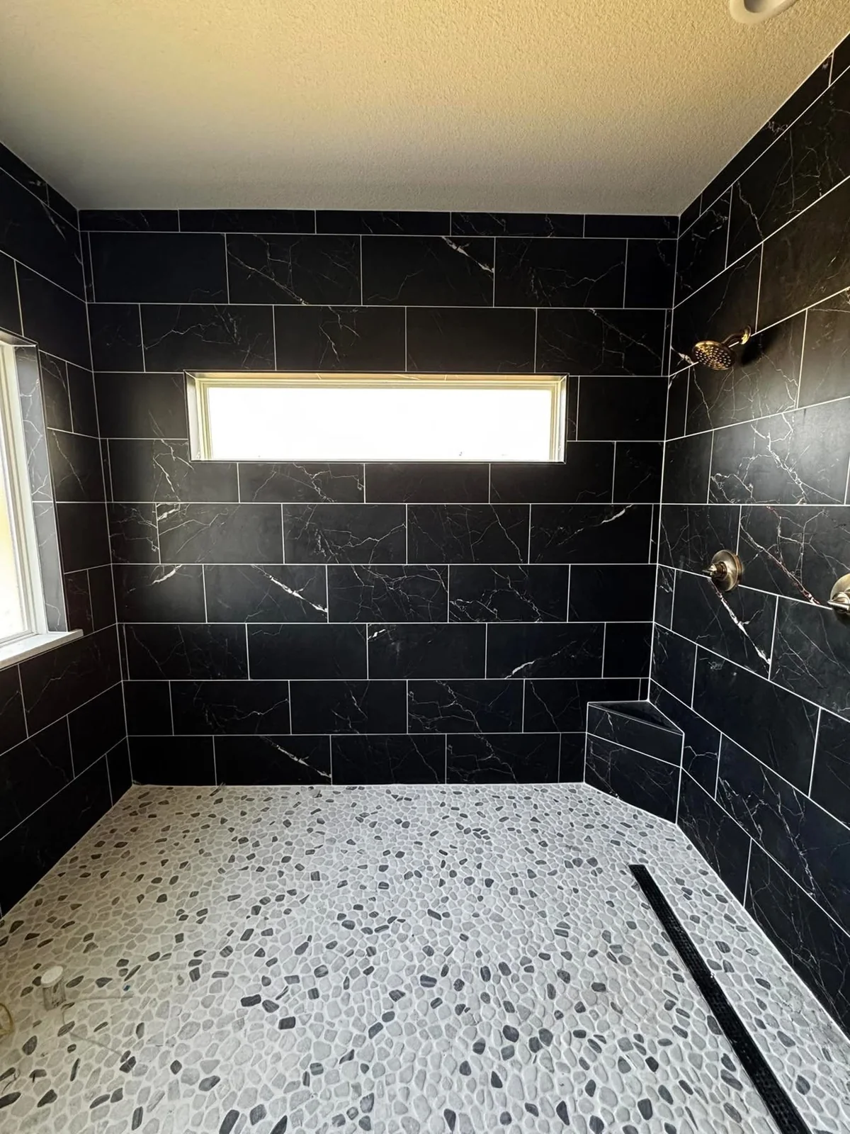 Stone shower with brass fixtures and freestanding bathtub