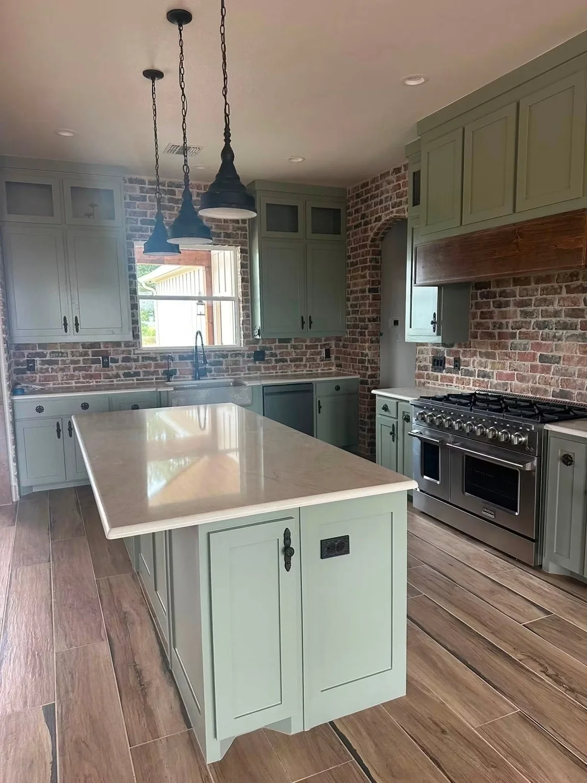 Sage cabinetry and warm wood-look tile flooring